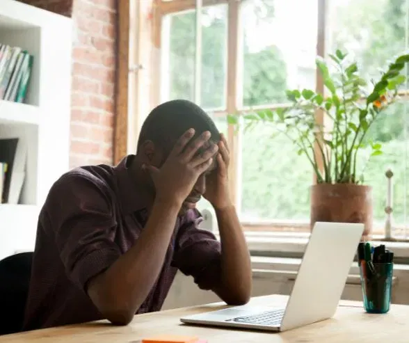 A man on his laptop showing visible frustration.